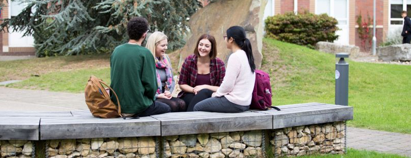Students sitting together on an outdoor campus bench in conversation