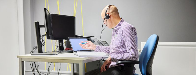 Adviser with a headset working at a desk, offering phone or online support